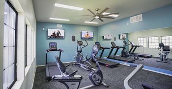 A gym with treadmills, exercise bikes, and a television.
